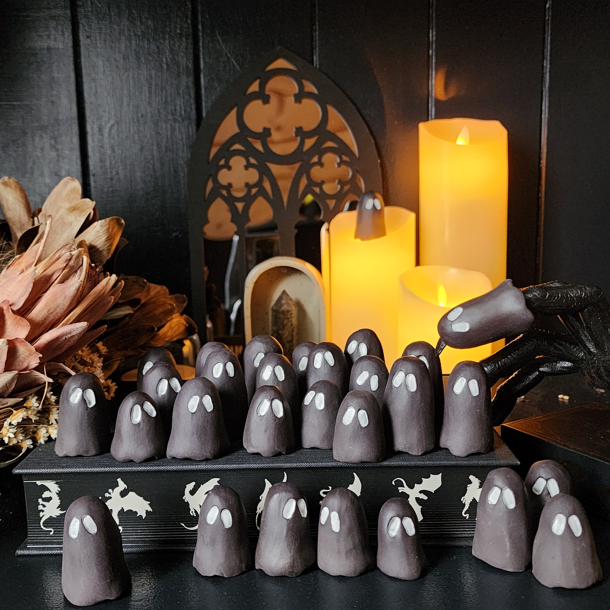 small matte black ceramic ghosts with white eyes sitting atop a book